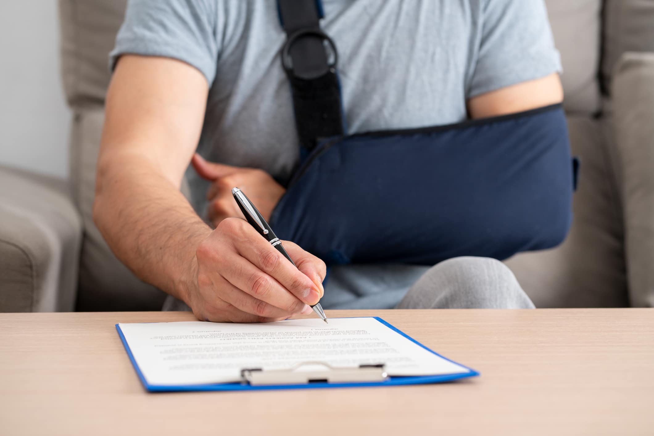 A man wearing a cast and signing forms to represent the cases handled by Theodoros & Rooth